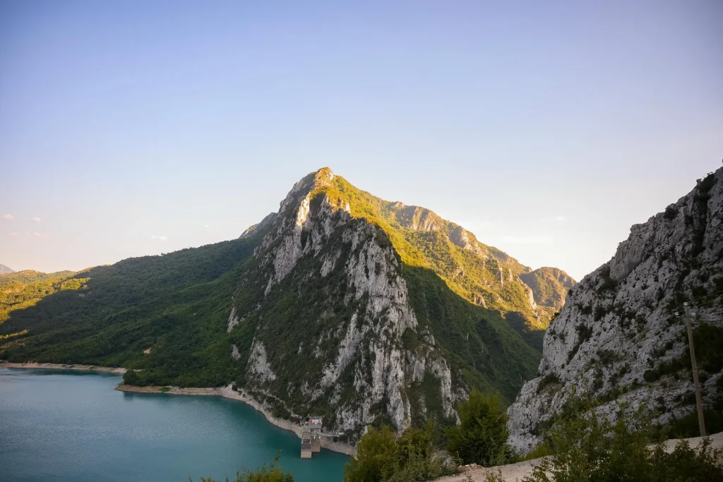 Bovilla Lake curving beneath the dramatic rocky face of Gamti Mountain