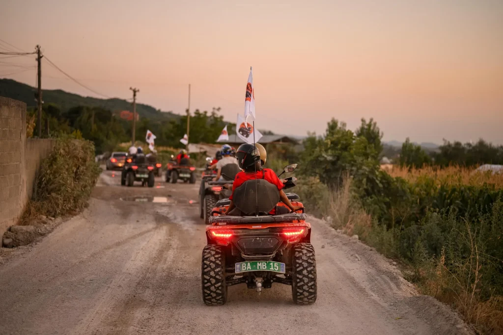 The ATV Tirana quad convoy returning along a country road at sunset