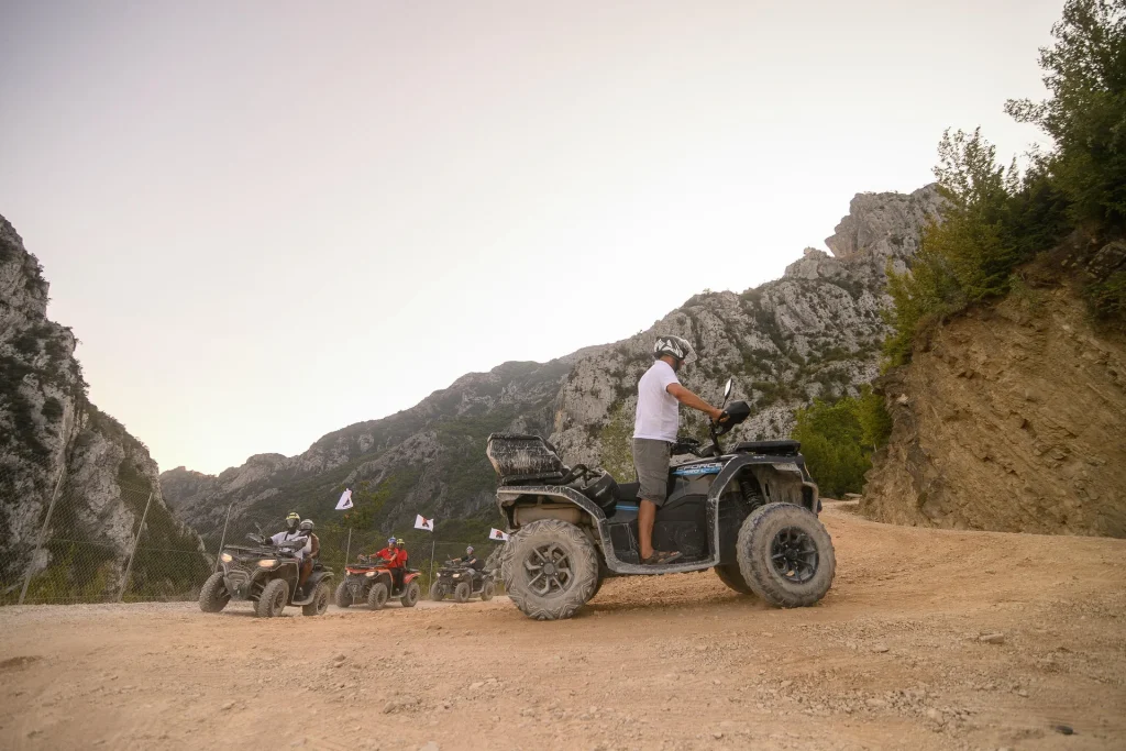 A quad rider crossing a dusty off-road turn during an ATV Tirana tour
