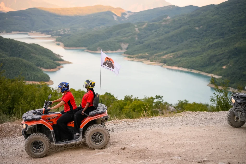 A rider on an orange quad passing the overlook with Bovilla Lake in the background