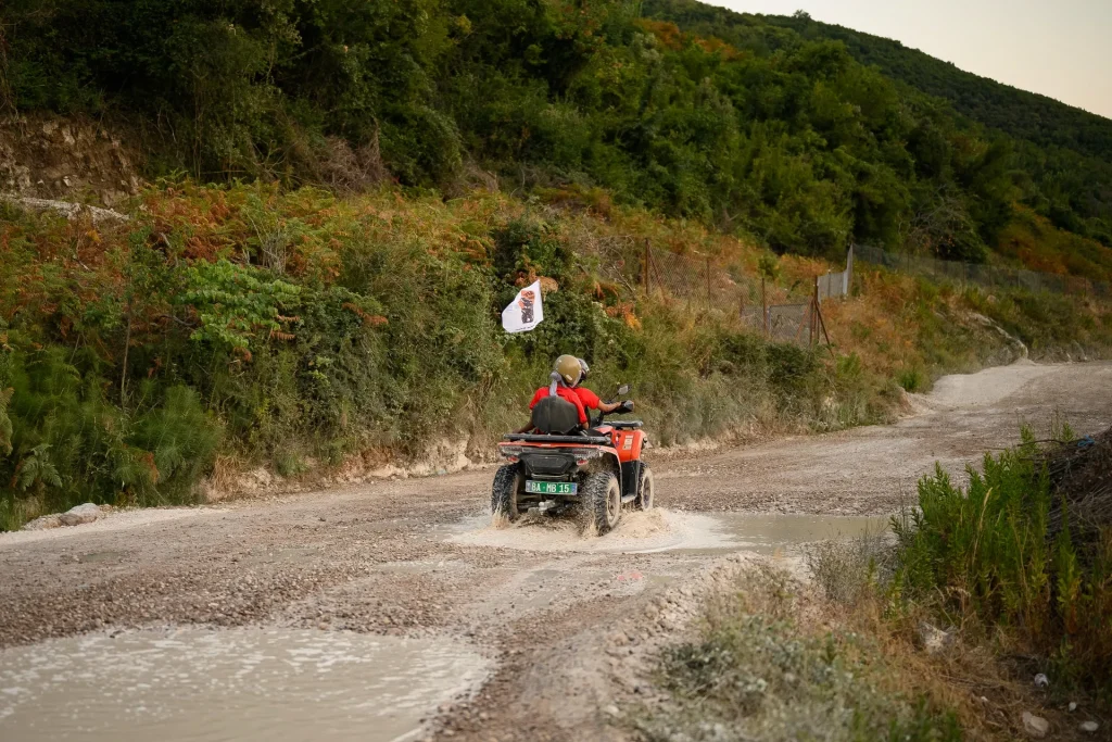 A solo ATV Tirana rider travelling along a pale rocky track in the hills