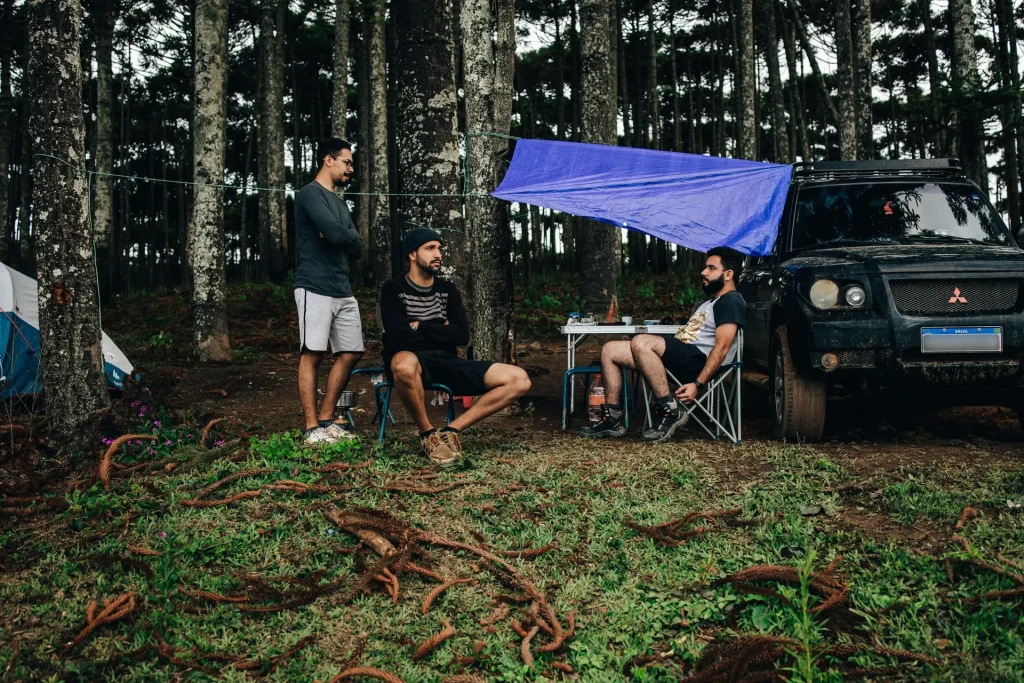 Illustrative group relaxing at a forest campsite beside their vehicle