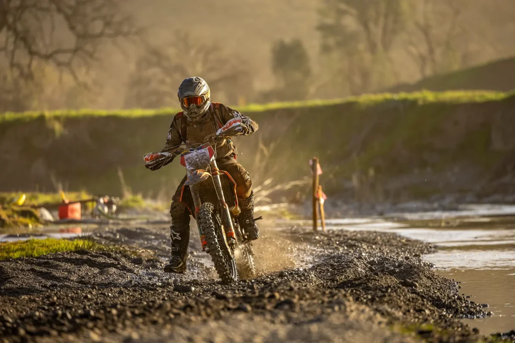Illustrative enduro rider powering through a muddy off-road section