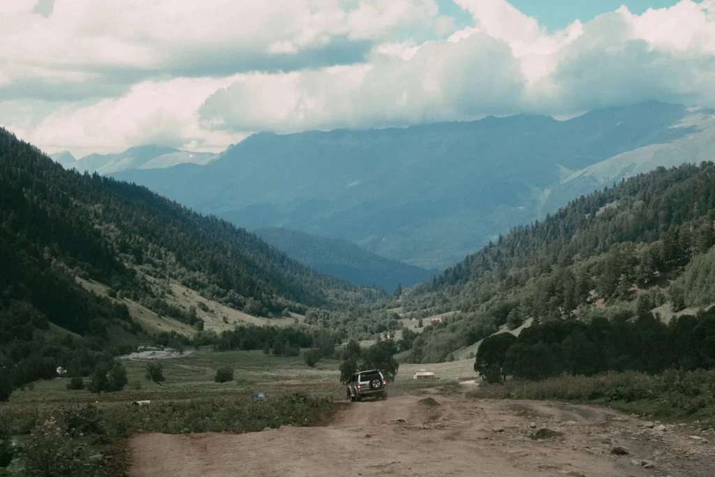 Illustrative off-road vehicle descending a rugged mountain-valley track