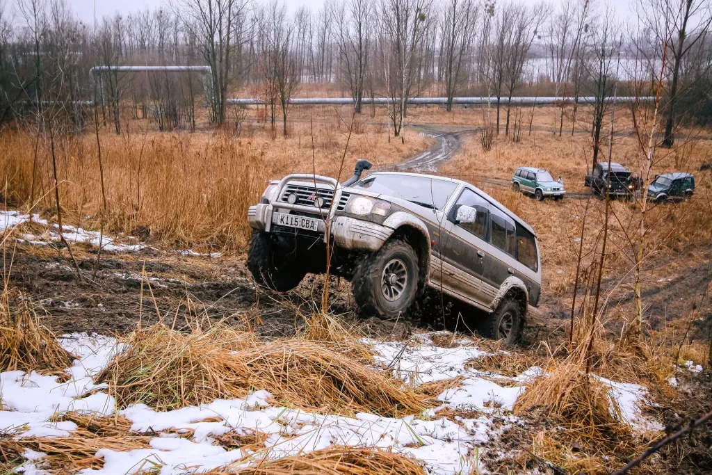 Illustrative 4x4 SUV climbing through a muddy off-road field